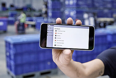 Someone showing a cellphone to the camera, where you can see Leadec Health and Safety Software Cority. 