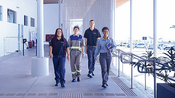 Four Leadec employees walking along a corridor inside a building.