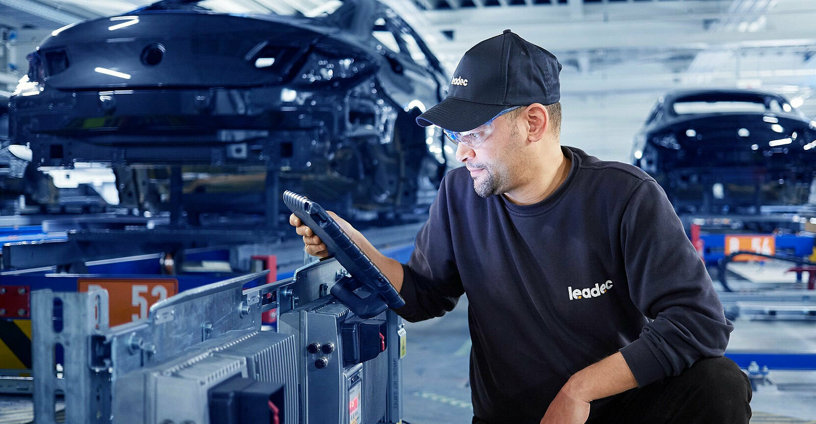 A Leadec employee configures an inverter at a conveyor belt.