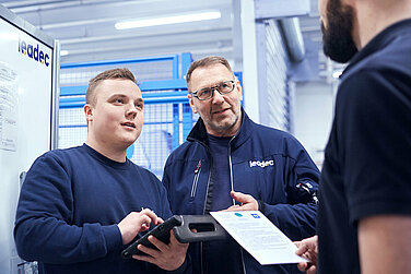Two Leadec employees inspecting machines and operating equipment in a production. 