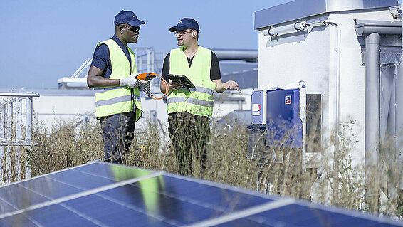 Two Leadec employees on factory roof with photovoltaic panels.