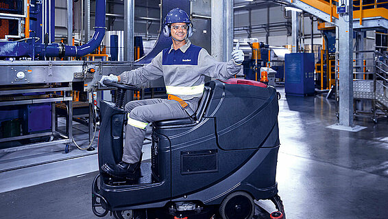 Leadec employee driving cleaning machine on shopfloor of Food & Beverage factory.