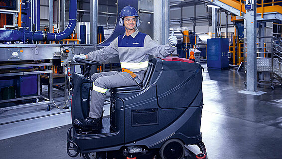Leadec employee driving cleaning machine on shopfloor of Food & Beverage factory.